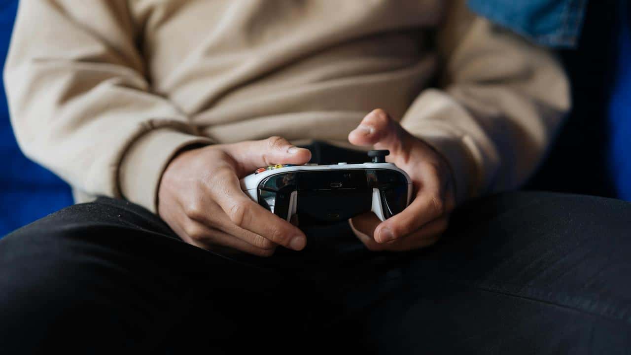 A person holding a video game controller while sitting down.