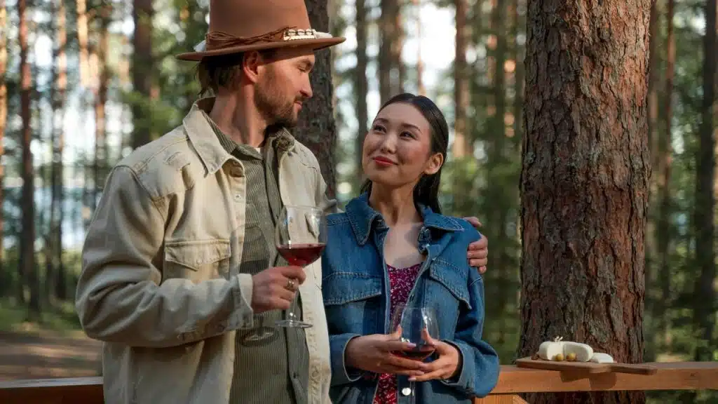 A couple sharing wine and a quiet moment together in a forest setting.