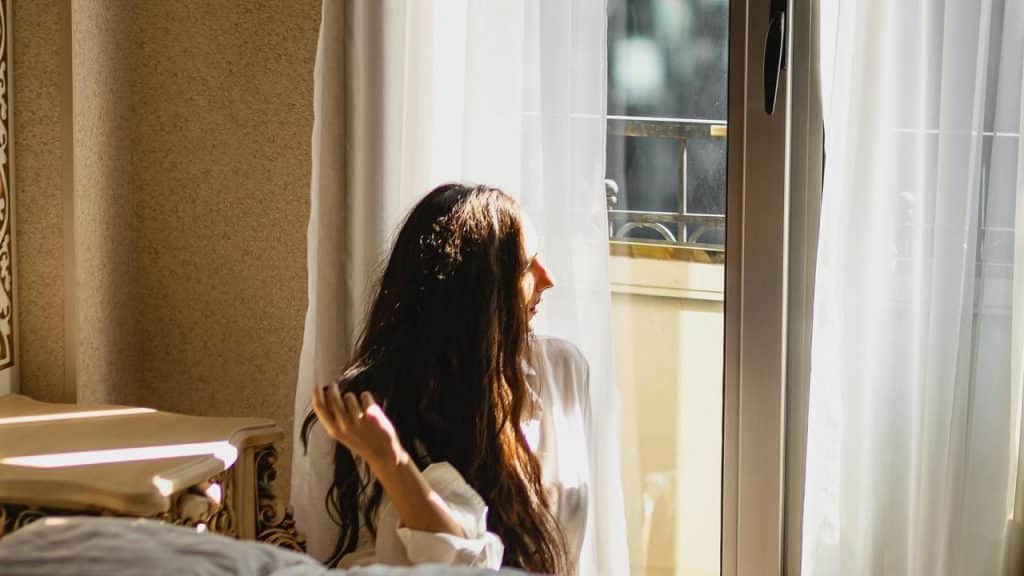 A woman sitting by a window with sunlight streaming in.