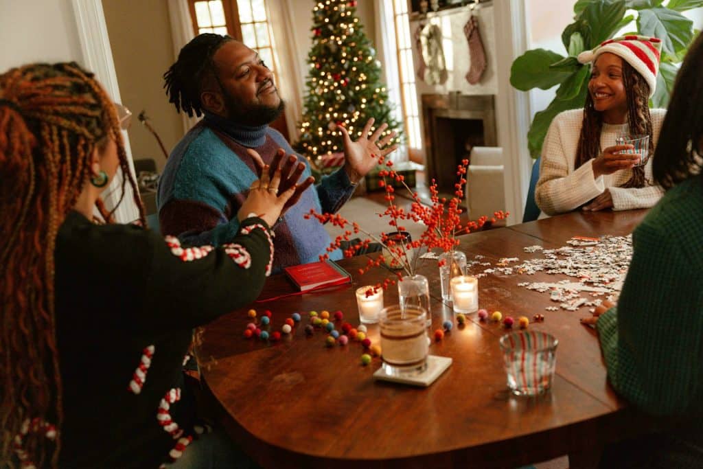 A group of people sitting around a wooden table, playing puzzles.