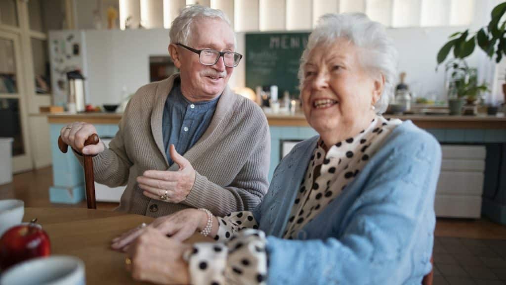 A smiling elderly woman and man enjoying breakfast.