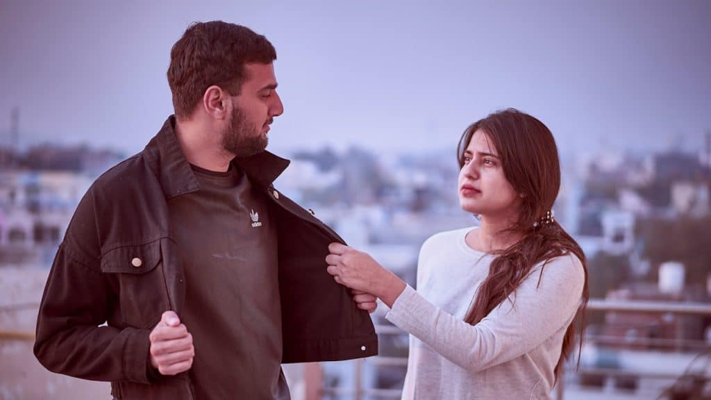 A woman grabbing a jacket of a man standing next to her.