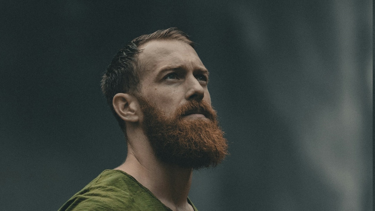 A bearded man looking upwards. 
