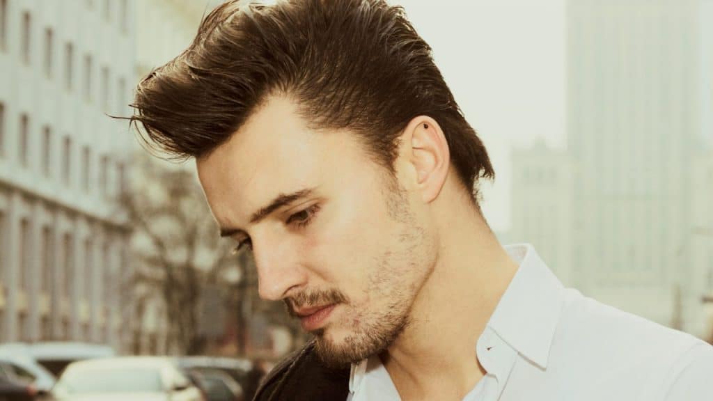 A man is staring downwards with a thoughtful expression.