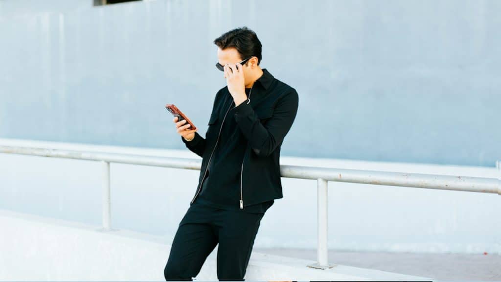 A man in a black suit talking on a cell phone.