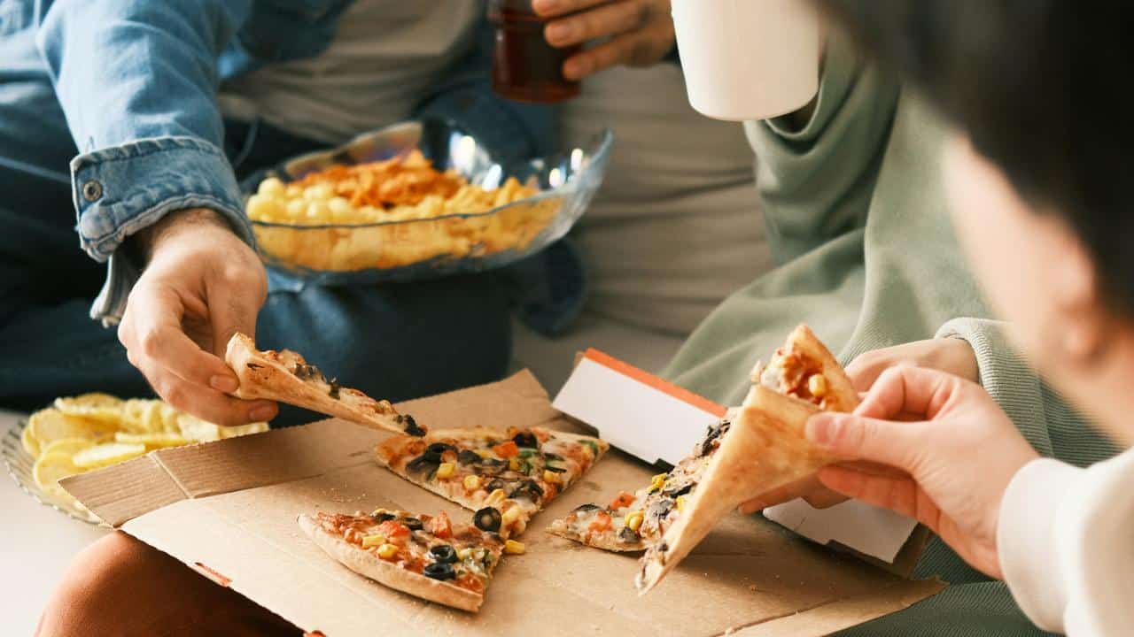 A group of people sharing pizza and snacks.