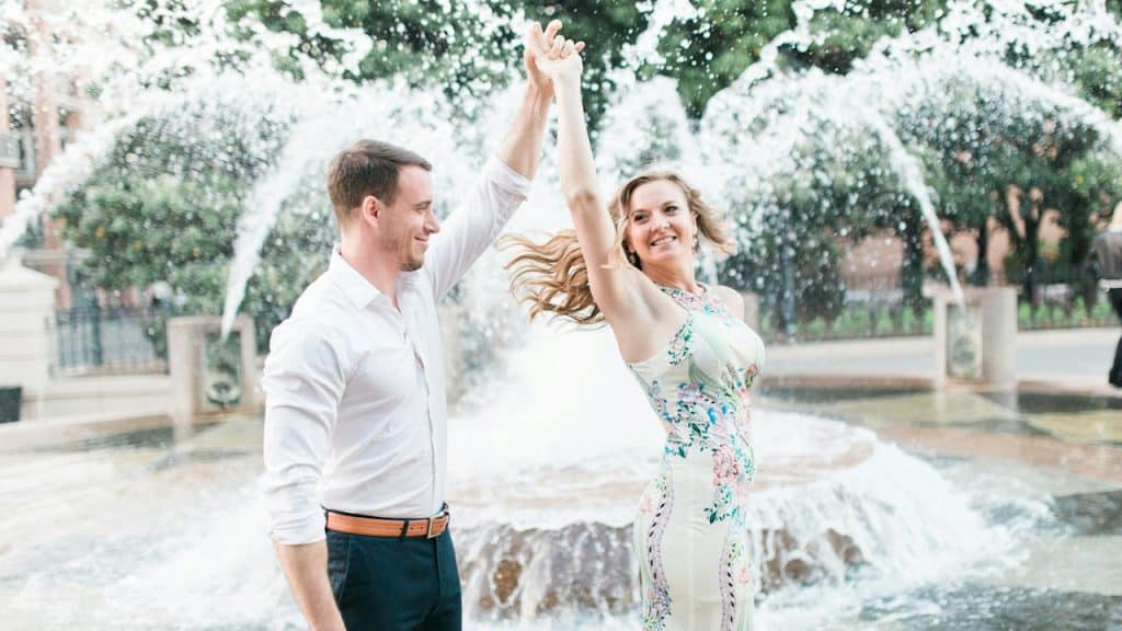 A man and woman dancing in front of a fountain.