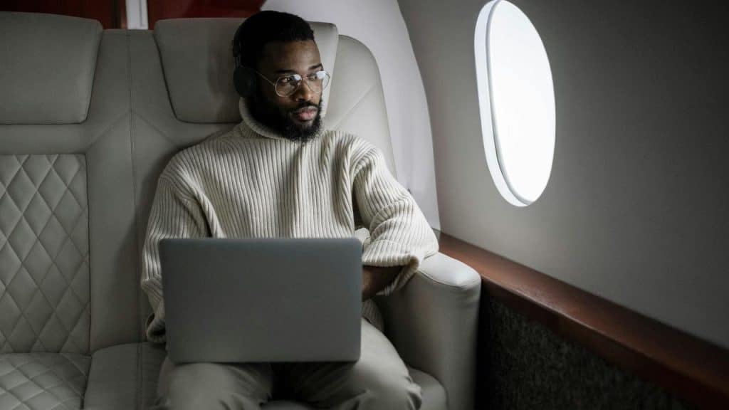A man using a laptop while seated on an airplane.