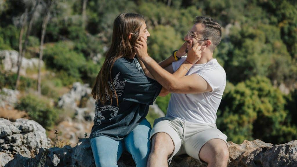 Couple playfully touching faces outdoors.