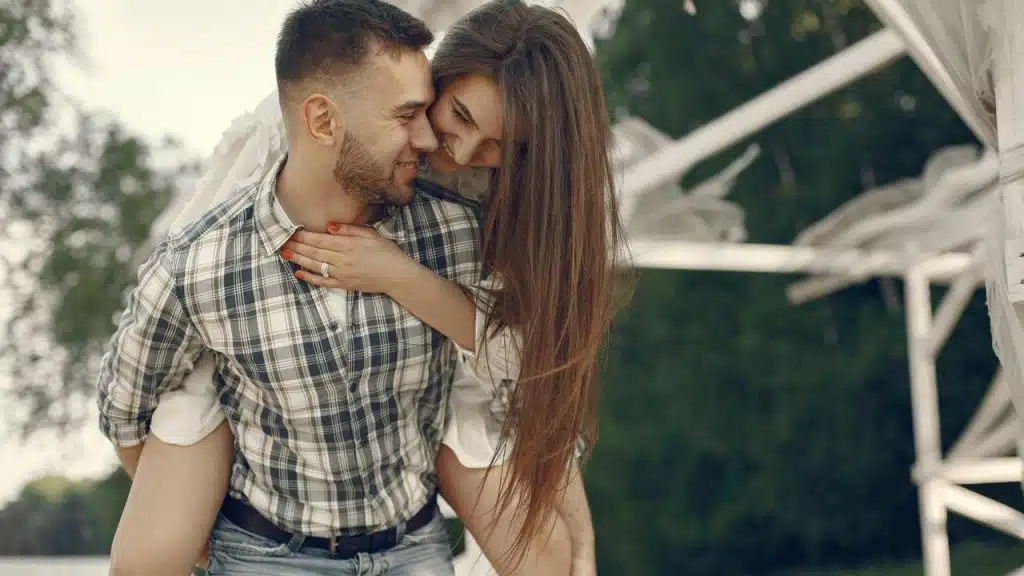 A couple sharing a playful piggyback embrace outdoors.