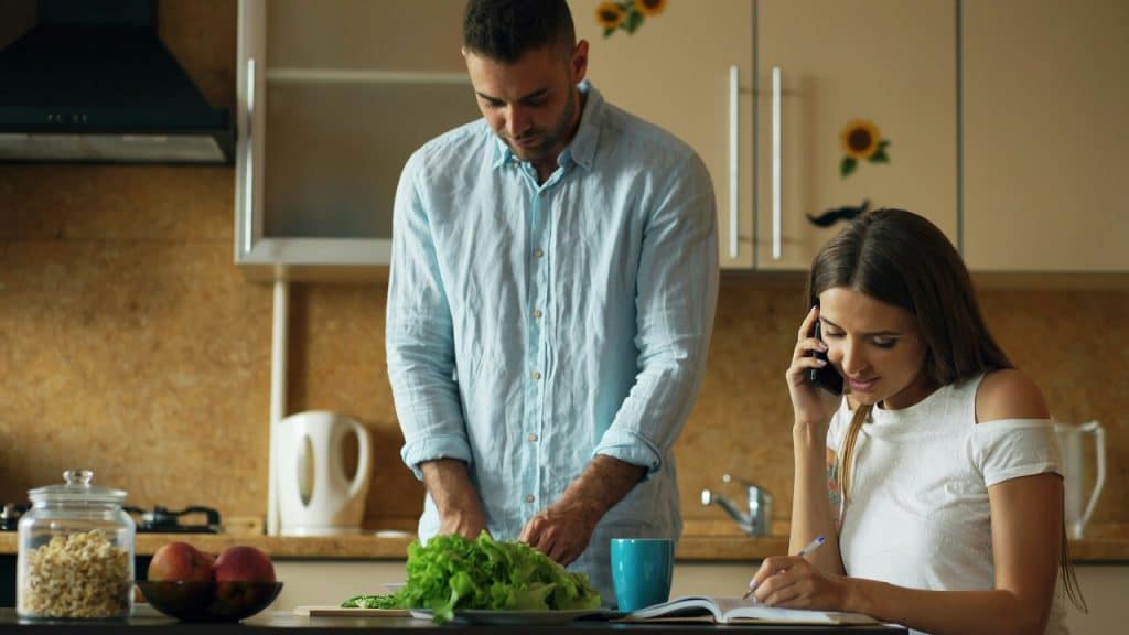 A couple ignoring each other in the kitchen