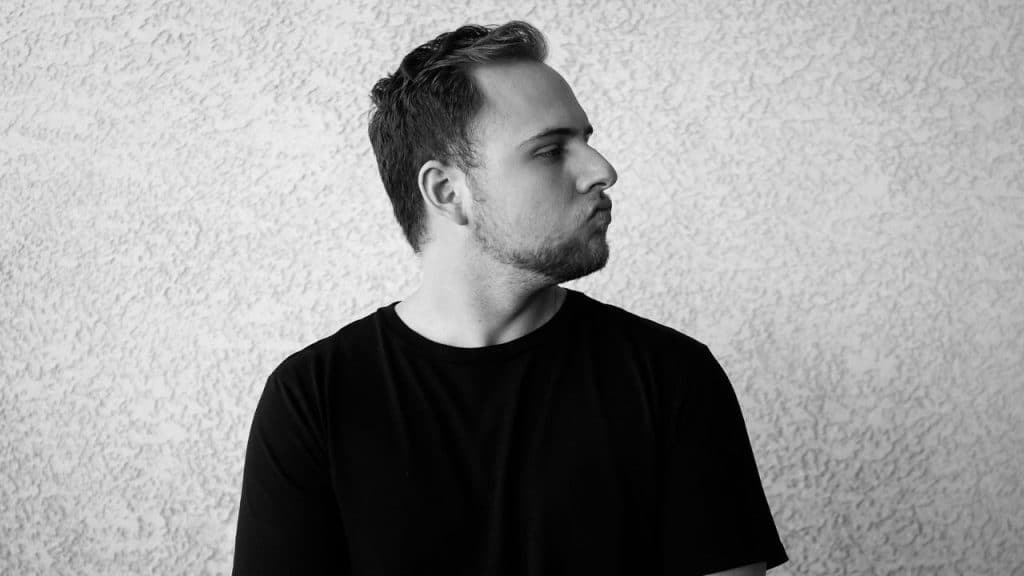 Black and white image of a man in a black shirt looking sharply to his right.