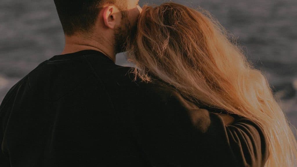 A couple embracing while looking out at the water.