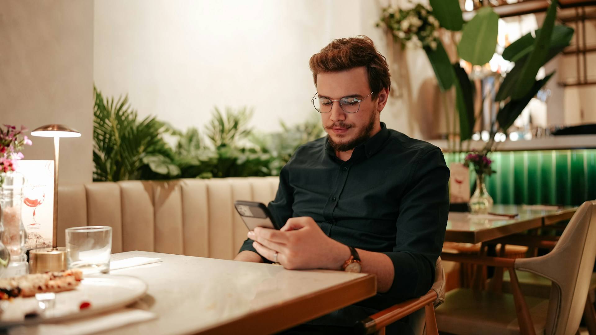 A man sitting at a table using his phone.