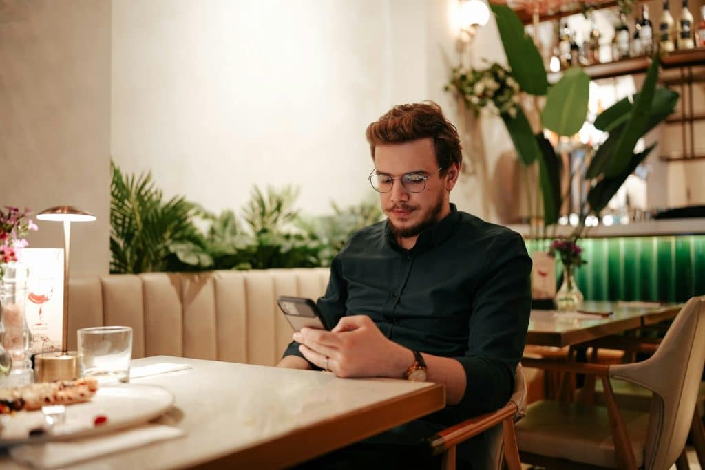 A man sitting at a table using his phone.