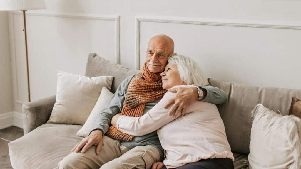 A couple cuddling warmly on a couch in a cozy living room.
