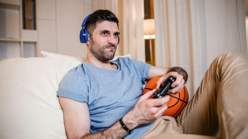 Man wearing blue headphones, holding a controller and a basketball.
