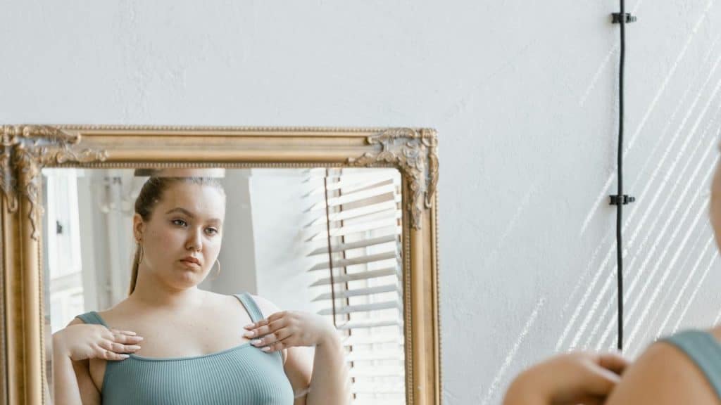 Plus-size woman in looking at her reflection in a mirror.