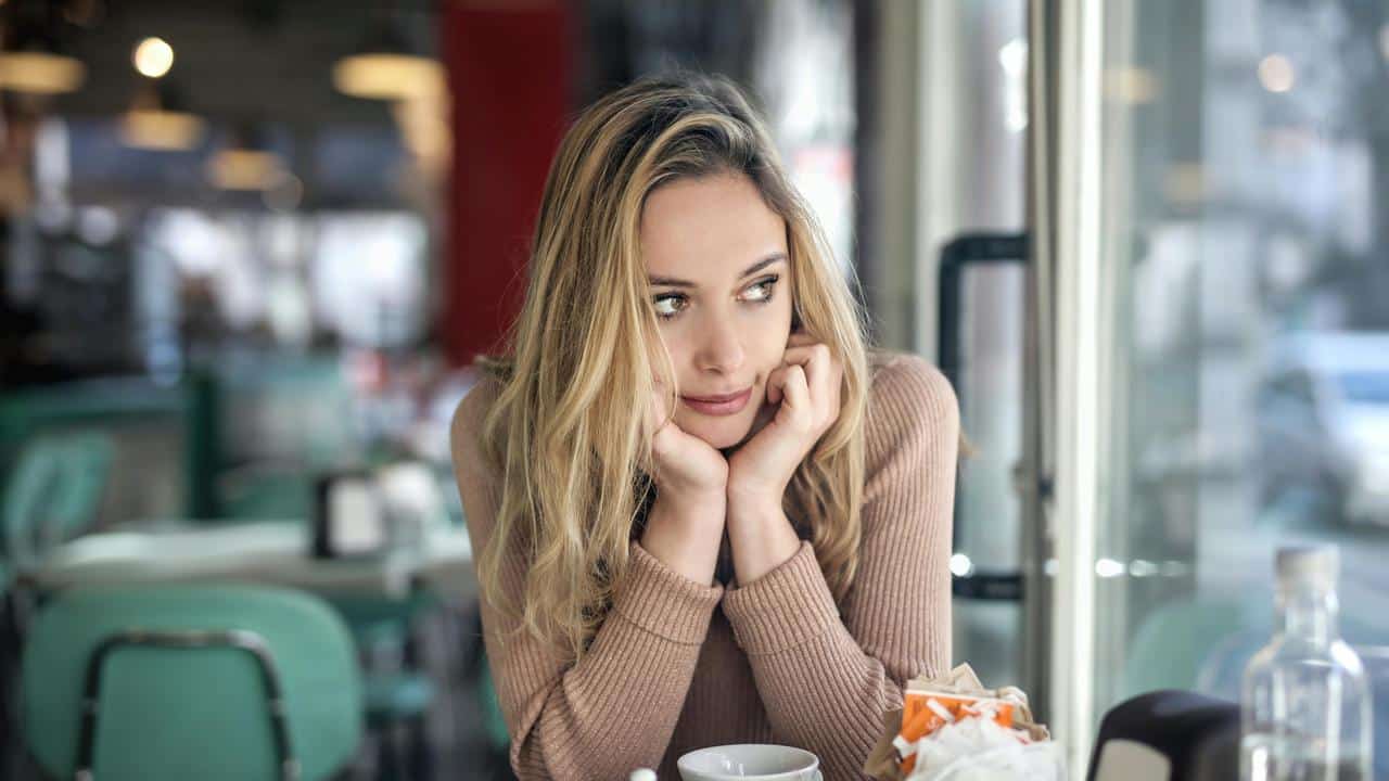 A person sitting in a café, gazing thoughtfully out the window.