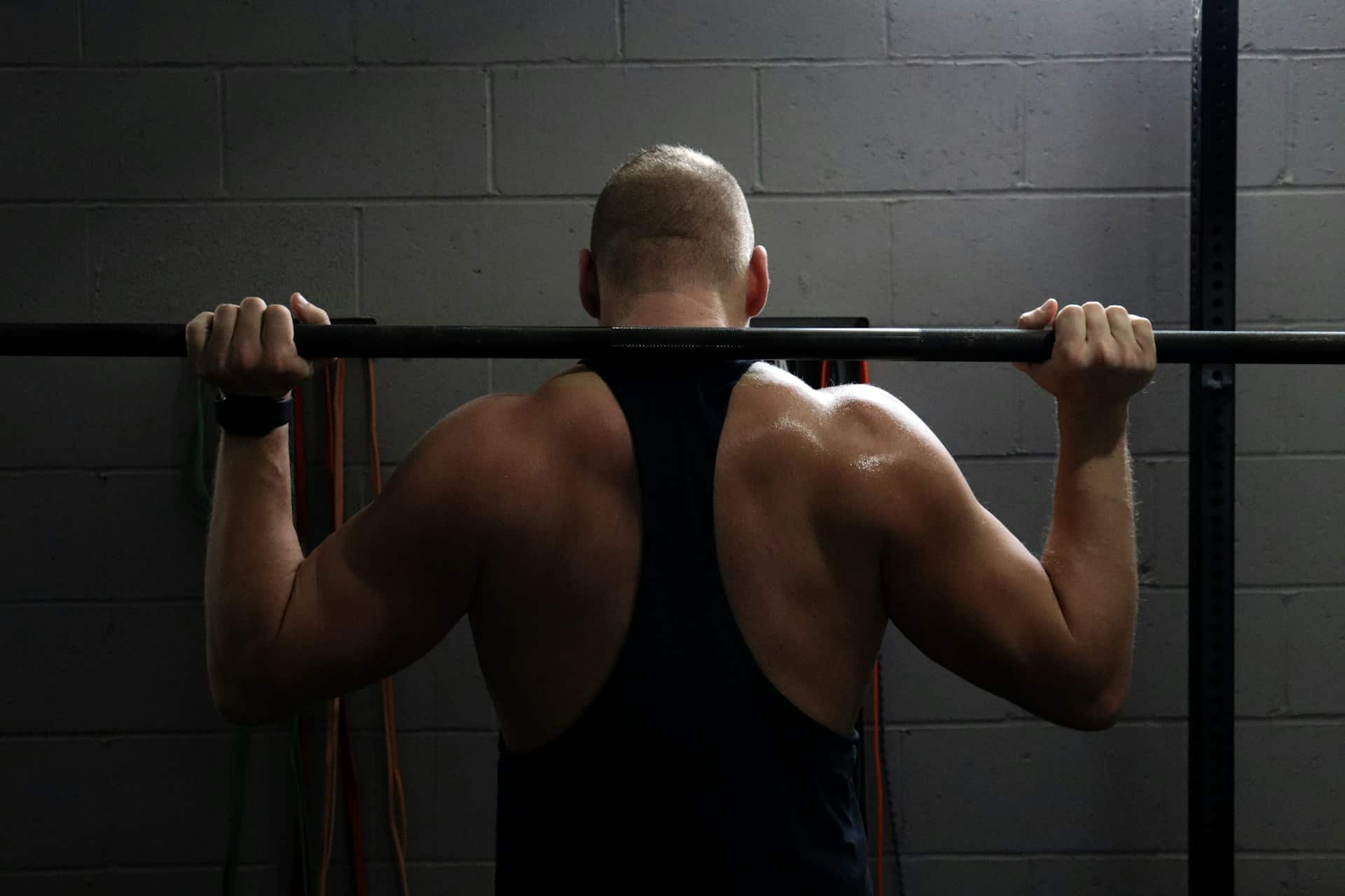 A back view of a man lifting weights.