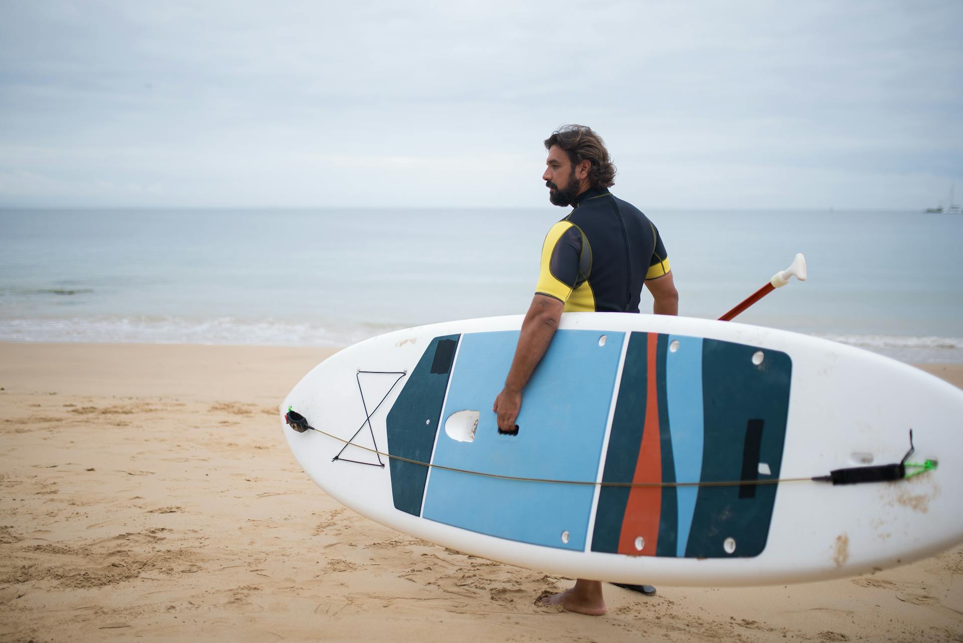 A man carrying a paddleboard.