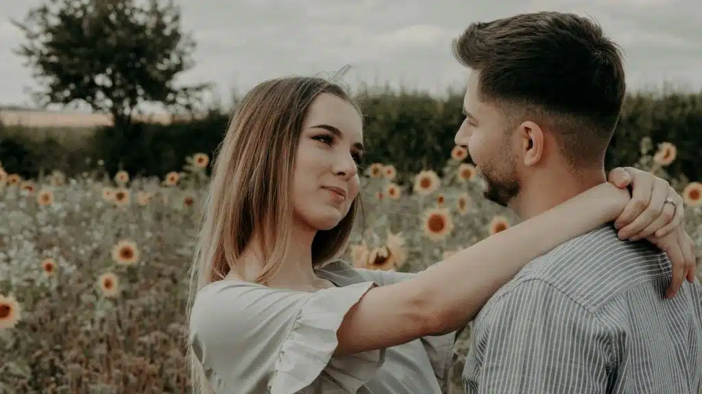 A man and a woman standing in a sunflower garden.