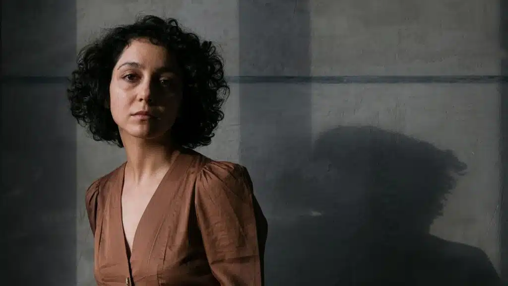 A woman in a brown dress standing in a dark room.