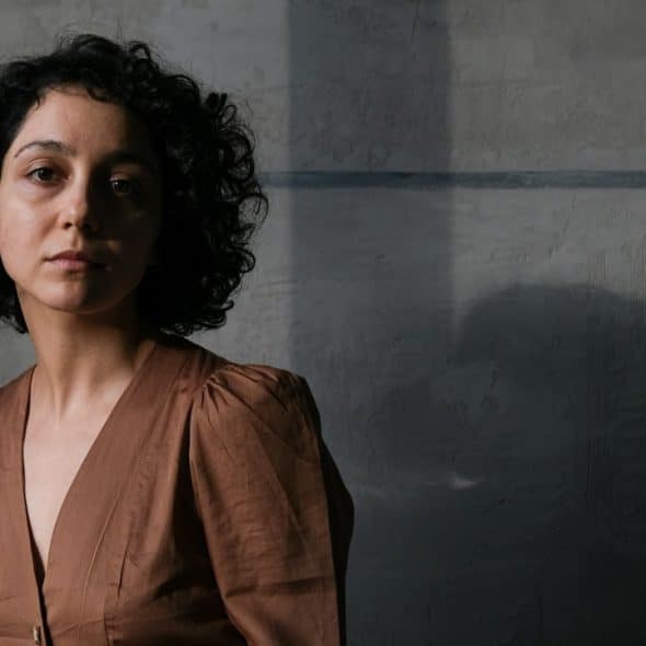 A woman in a brown dress standing in a dark room.