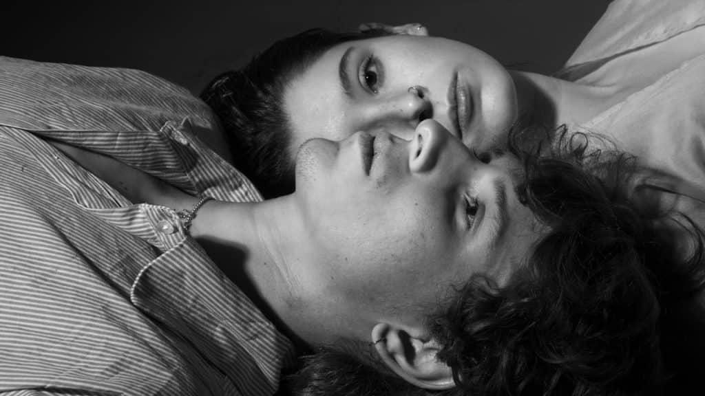 A couple lying on the ground with their heads next to each other in opposite directions.