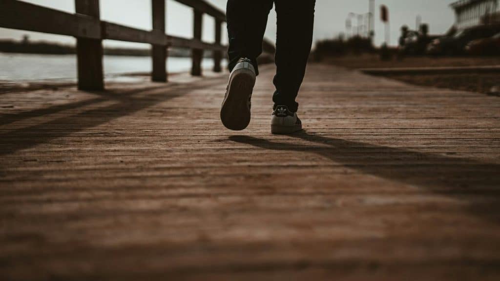 A person walking on a wooden boardwalk.