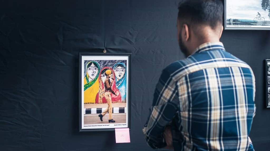 A man looking at framed artwork in a gallery.