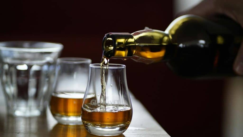 A bottle pouring whiskey into a glass.
