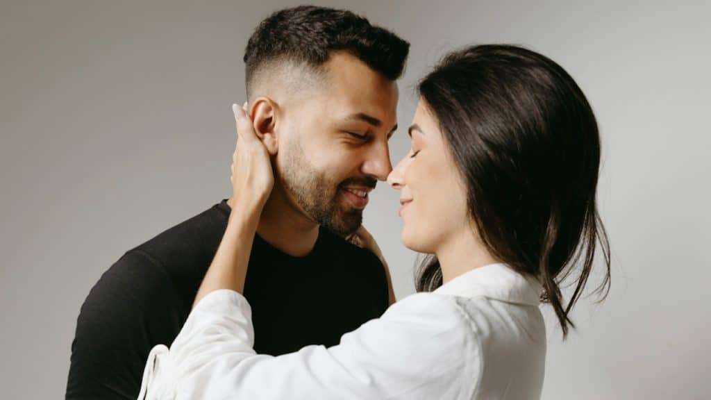 A couple with closed eyes touching noses and smiling.
