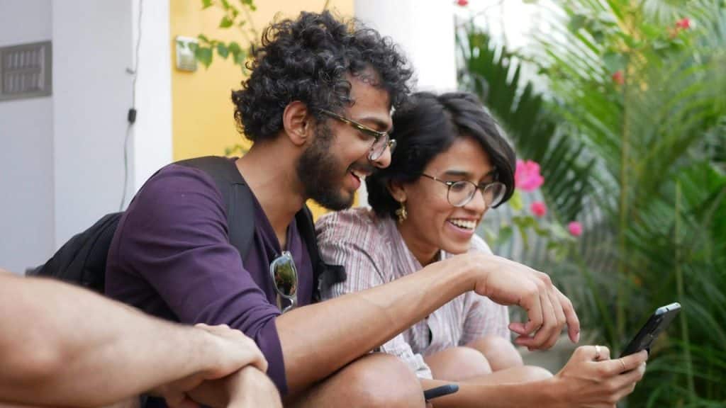 A couple wearing glasses using a phone and smiling. 