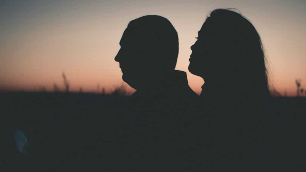 Silhouette of a couple standing outdoors at sunset.
