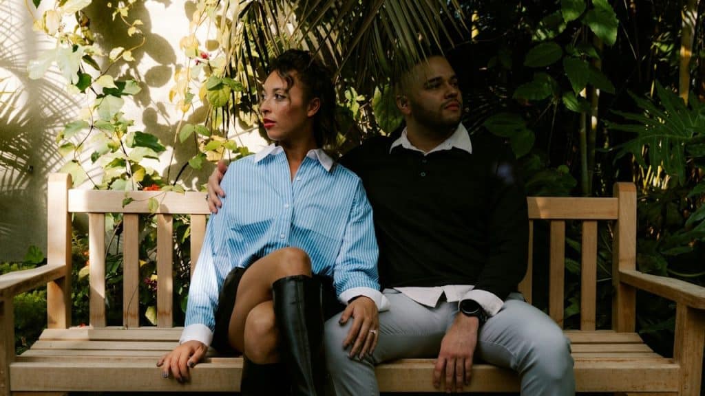 A couple sitting on a bench while looking in opposite directions.