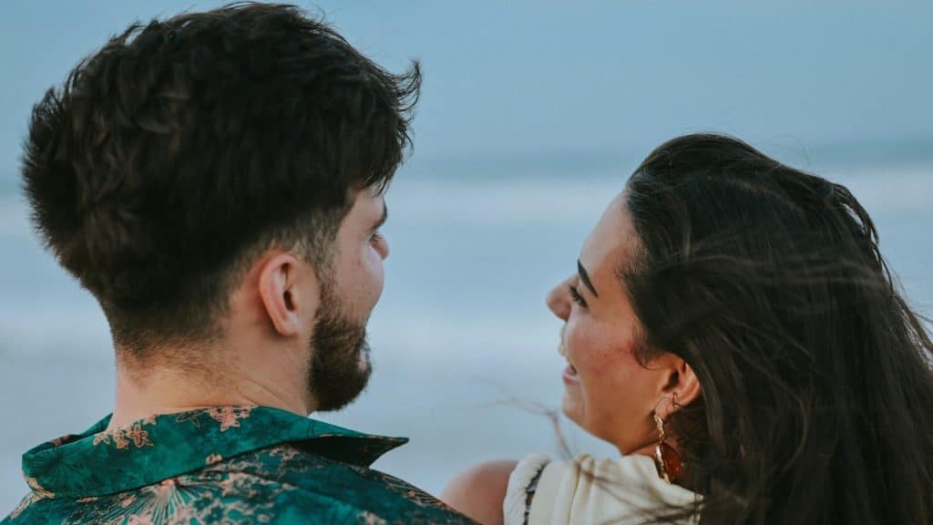 A couple looking at each other by the ocean.