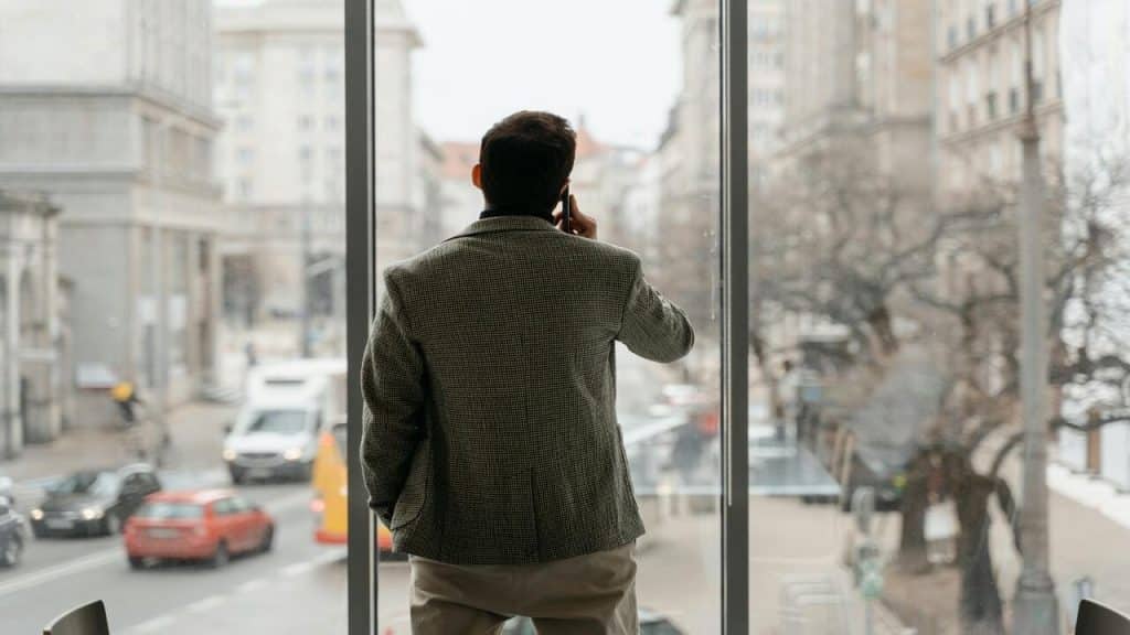 A man looking out the window while on the phone