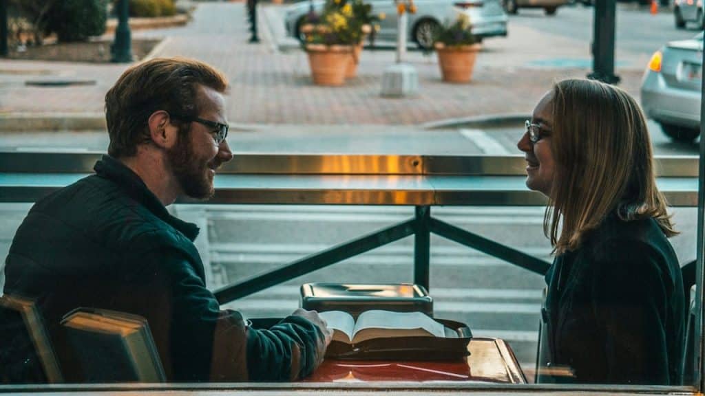 A man and a woman reading a book in a library.