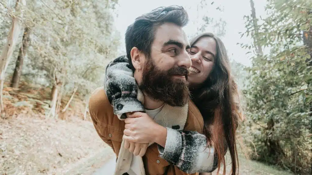 A man carrying a woman on his back in the woods.