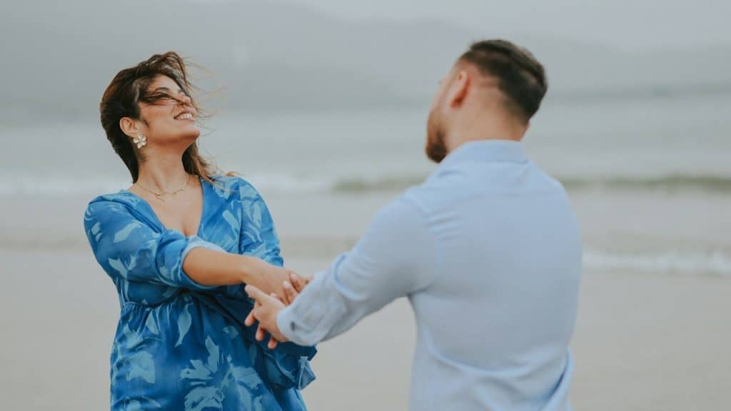 A man and a woman dancing with each other on a beach.