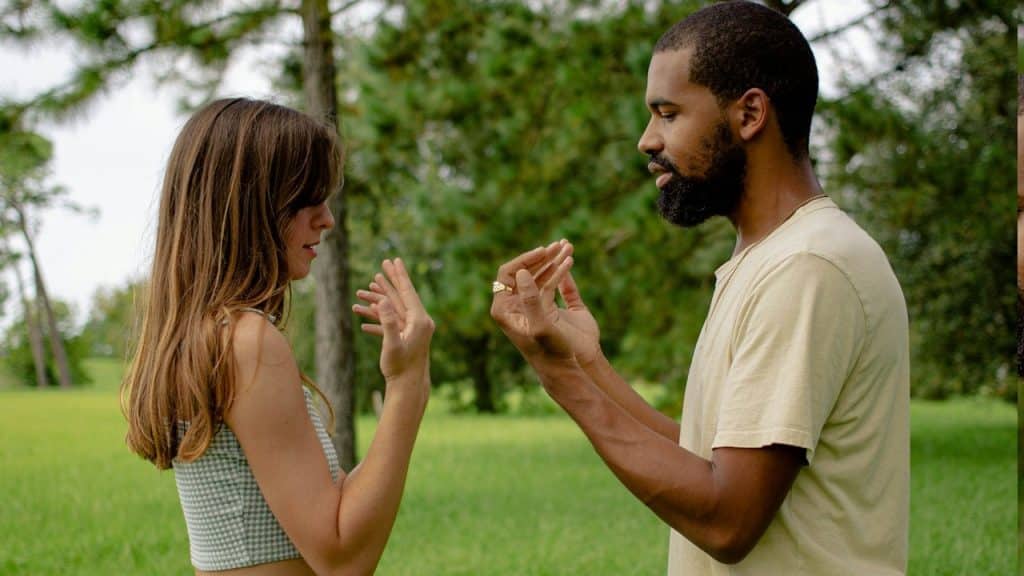 A man and a woman standing next to each other in a field. 