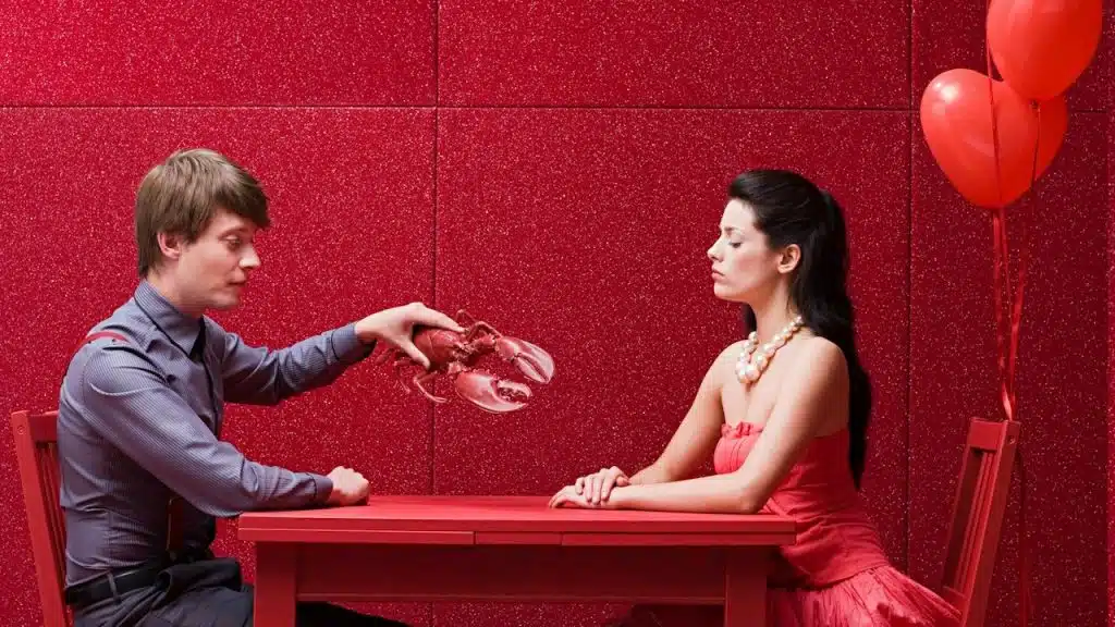 A man and a woman sitting at a table with red balloons.