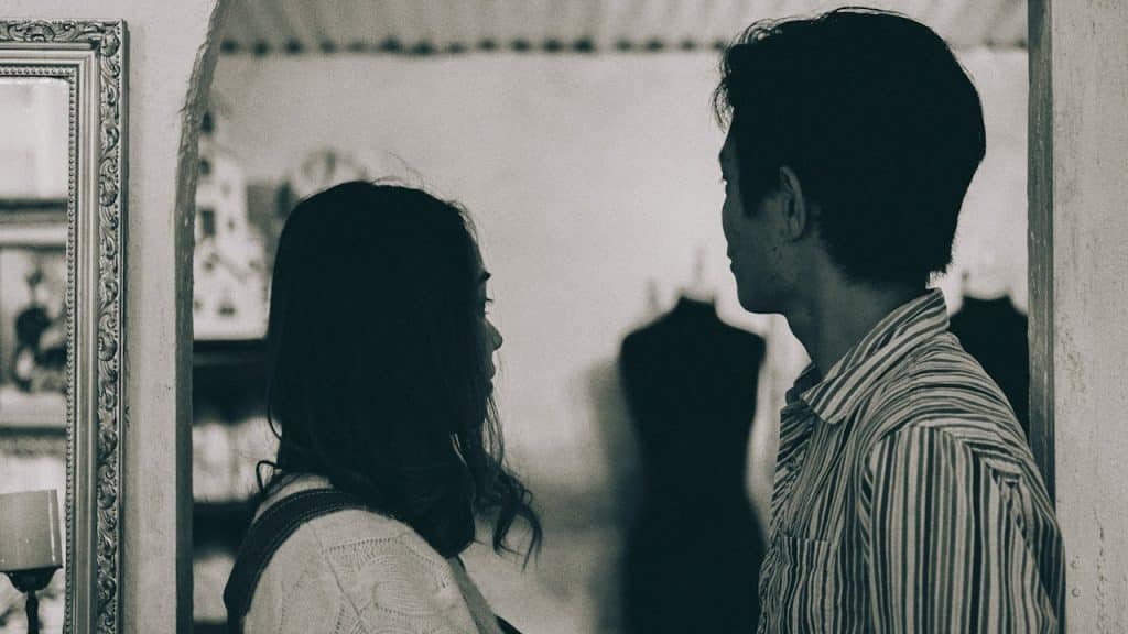 A man and woman standing in grayscale photography.