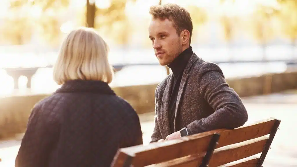 A couple sitting on a bech and talking.