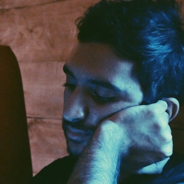 A man leaning his face on his left hand.