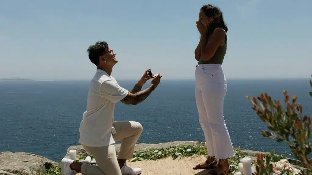 A man kneeling down next to a woman on top of a cliff.