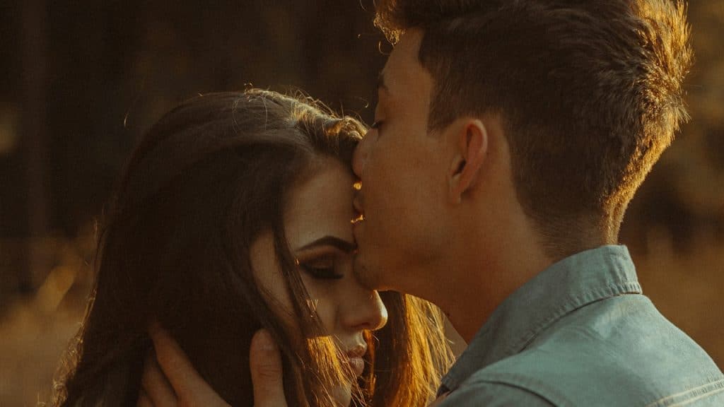 A man kissing a woman's forehead.