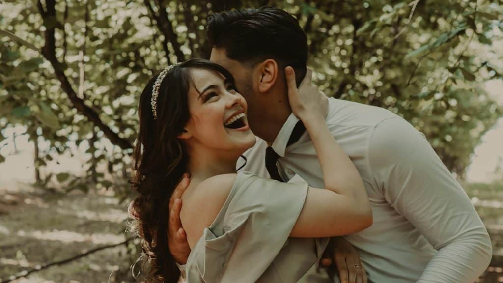 A couple kissing in a garden.