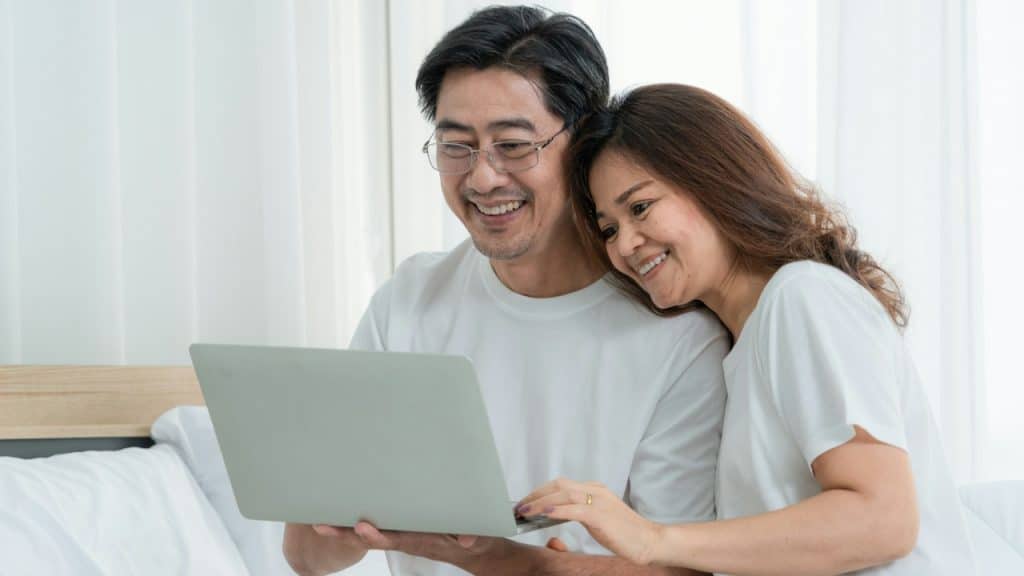 A middle-aged couple working on a laptop and smiling.